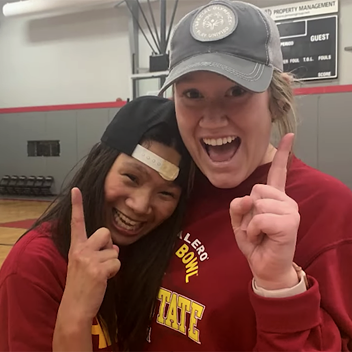 An Iowa State student poses with a young girl at an event in the gym.