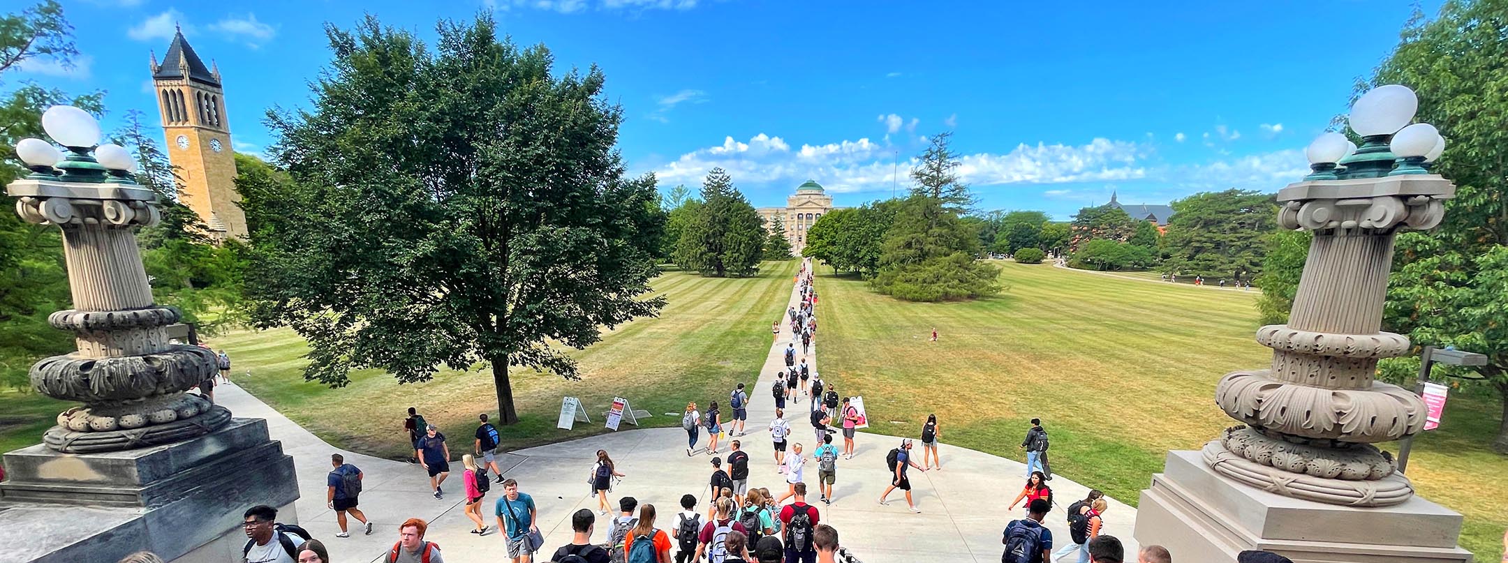 View of sunny central campus as students climb the stairs of Curtiss Hall.